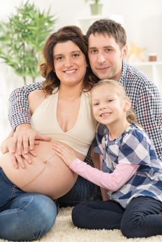 Portrait of a beautiful young family cuddling the woman's pregnant belly. 