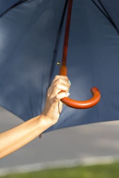 Arm girls with beautiful manicure holding blue umbrellas on the street