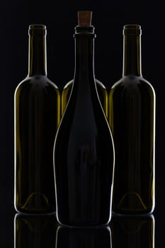 Four different bottles of wine on the black glass.