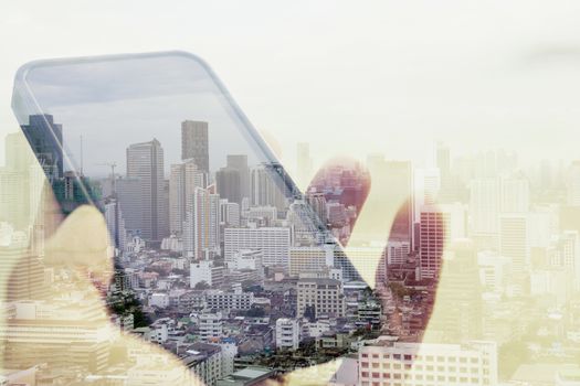 Double exposure image of businessman using smart phone with cityscape background