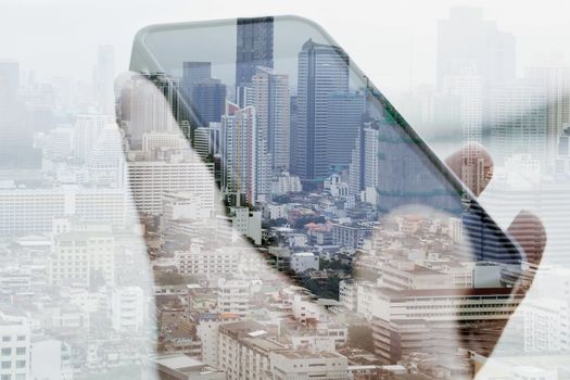 Double exposure image of businessman using smart phone with cityscape background
