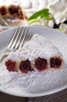 a piece of cherry pie sprinkled with powder sugar on a plate