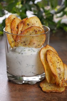 Homemade potato chips and spicy dip served in glass.