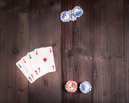 Chips and Four aces vintage poker game playing cards on a weathered wood table,view from above.