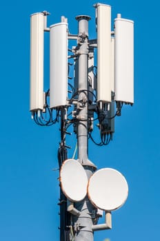 closeup of cellular antenna between trees on blue sky