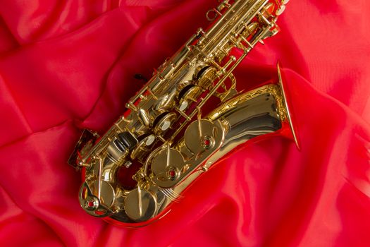 beautiful golden saxophone on delicate red silk background