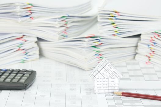 House and pencil on finance account have blur calculator and pile paperwork of report with colorful paperclip as background.