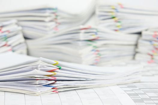 Pile paperwork of report with colorful paperclip on finance account have blur pile overload document as background.