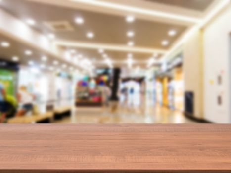 Wooden board empty table in front of blurred background. Perspective dark wood table over blur in shopping mall hall. Mock up for display or montage your product.