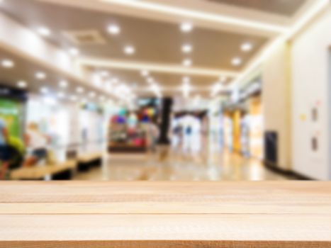Wooden board empty table in front of blurred background. Perspective light wood table over blur in shopping mall hall. Mock up for display or montage your product.