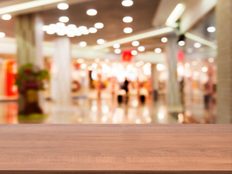 Wooden board empty table in front of blurred background. Perspective dark wood table over blur in shopping mall hall. Mock up for display or montage your product.