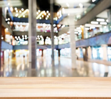 Wooden board empty table in front of blurred background. Perspective light wood table over blur in shopping mall hall. Mock up for display or montage your product.