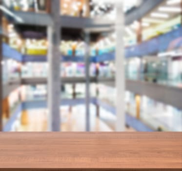 Wooden board empty table in front of blurred background. Perspective dark wood table over blur in shopping mall hall. Mock up for display or montage your product.