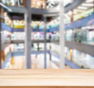 Wooden board empty table in front of blurred background. Perspective light wood table over blur in shopping mall hall. Mock up for display or montage your product.