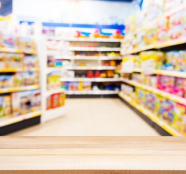 Wooden board empty table in front of blurred background. Perspective light wood table over blur in kids toy store. Mock up for display or montage your product.