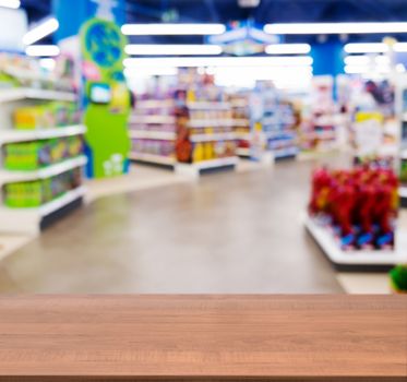 Wooden board empty table in front of blurred background. Perspective dark wood table over blur in kids toy store. Mock up for display or montage your product.