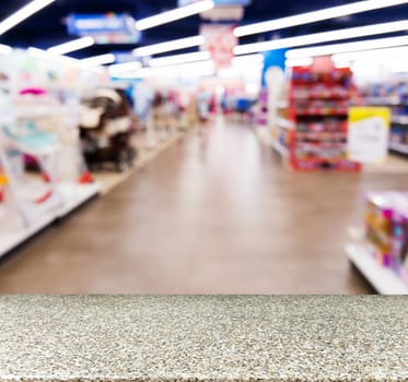 Marble board empty table in front of blurred background. Perspective marble table over blur in kids toy store. Mock up for display or montage your product.