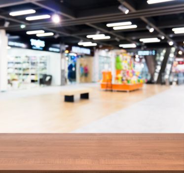 Wooden board empty table in front of blurred background. Perspective dark wood table over blur in shopping mall hall. Mock up for display or montage your product.