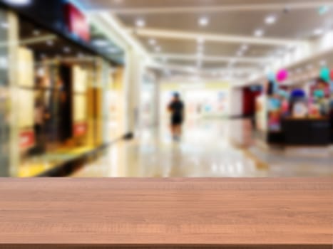 Wooden board empty table in front of blurred background. Perspective dark wood table over blur in shopping mall hall. Mock up for display or montage your product.