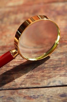 Magnifying glass with long shadow on wooden background