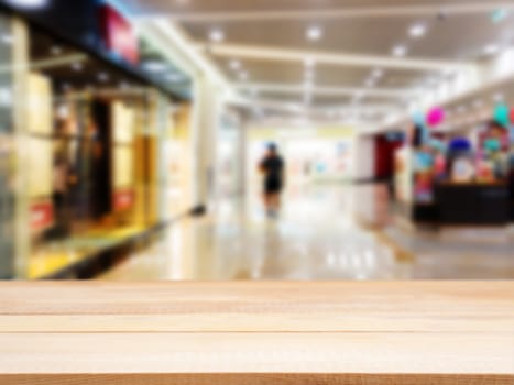 Wooden board empty table in front of blurred background. Perspective light wood table over blur in shopping mall hall. Mock up for display or montage your product.