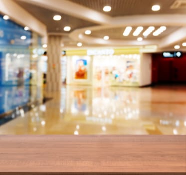 Wooden board empty table in front of blurred background. Perspective dark wood table over blur in shopping mall hall. Mock up for display or montage your product.