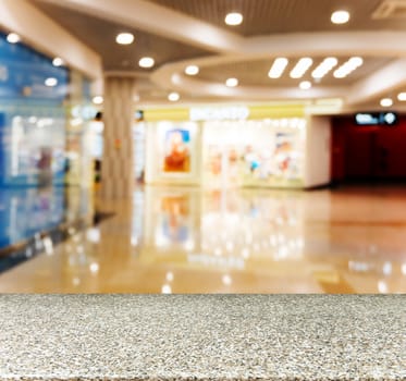 Marble board empty table in front of blurred background. Perspective marble table over blur in shopping mall hall. Mock up for display or montage your product.