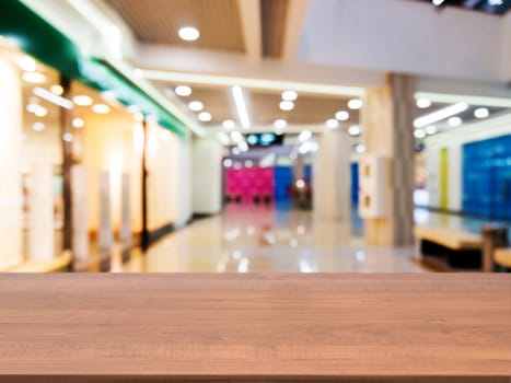 Wooden board empty table in front of blurred background. Perspective dark wood table over blur in shopping mall hall. Mock up for display or montage your product.