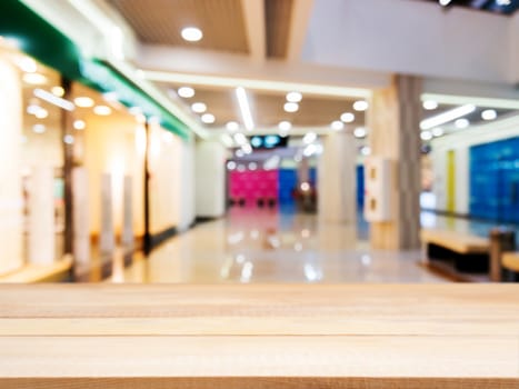 Wooden board empty table in front of blurred background. Perspective light wood table over blur in shopping mall hall. Mock up for display or montage your product.