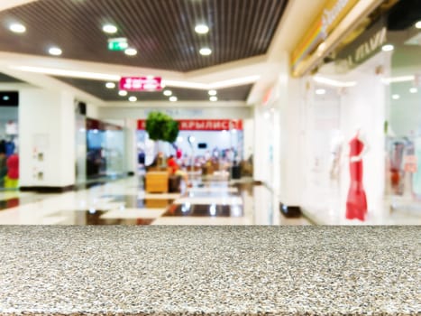 Marble board empty table in front of blurred background. Perspective marble table over blur in shopping mall hall. Mock up for display or montage your product.