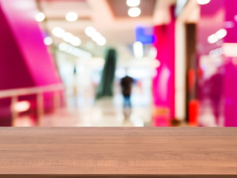 Wooden board empty table in front of blurred background. Perspective dark wood table over blur in shopping mall hall. Mock up for display or montage your product.