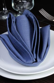 Folded textile cloth in the form of flower bud on a plate