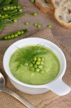 A plate of soup puree of green peas with dill on a table