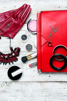Fashionable ladies handbag with cosmetics and decorations on light background