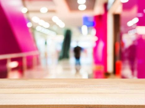 Wooden board empty table in front of blurred background. Perspective light wood table over blur in shopping mall hall. Mock up for display or montage your product.