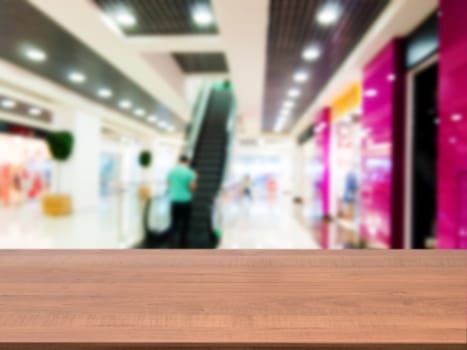 Wooden board empty table in front of blurred background. Perspective dark wood table over blur in shopping mall hall. Mock up for display or montage your product.