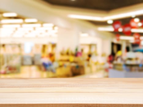 Wooden board empty table in front of blurred background. Perspective light wood table over blur in shopping mall hall. Mock up for display or montage your product.