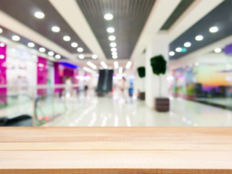 Wooden board empty table in front of blurred background. Perspective light wood table over blur in shopping mall hall. Mock up for display or montage your product.