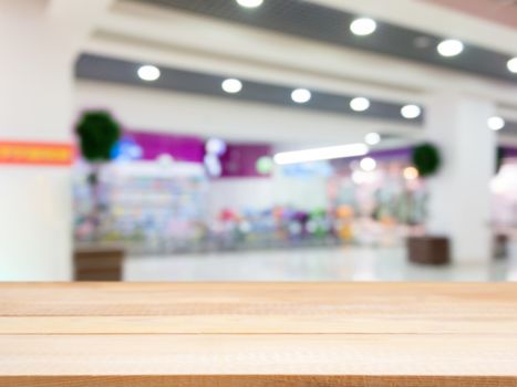 Wooden board empty table in front of blurred background. Perspective light wood table over blur in shopping mall hall. Mock up for display or montage your product.