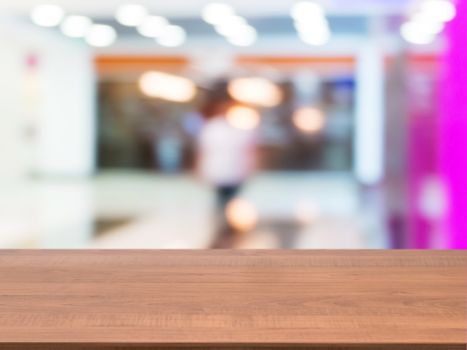 Wooden board empty table in front of blurred background. Perspective dark wood table over blur in shopping mall hall. Mock up for display or montage your product.