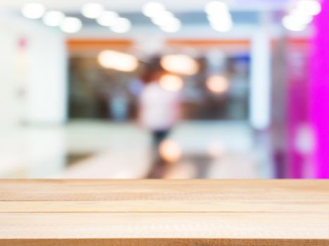 Wooden board empty table in front of blurred background. Perspective light wood table over blur in shopping mall hall. Mock up for display or montage your product.