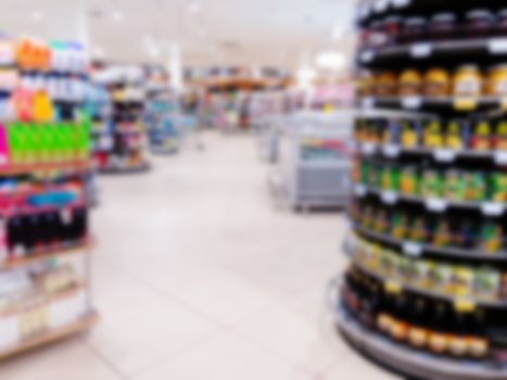 Abstract blurred supermarket aisle with colorful shelves and unrecognizable customers as background