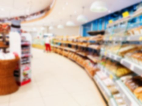 Abstract blurred supermarket aisle with colorful shelves and unrecognizable customers as background