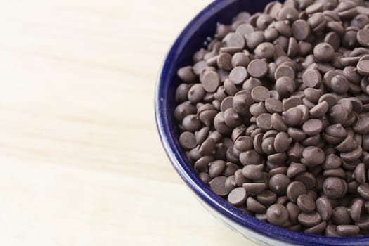 Chocolate chips in blue bowl close up with copy space