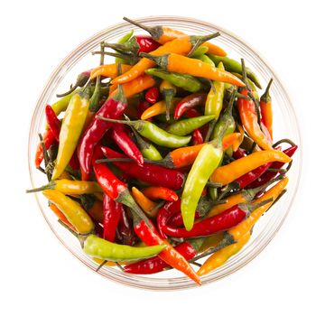 Bowl of yellow, red and green hot chili peppers isolated on white.  View from above.