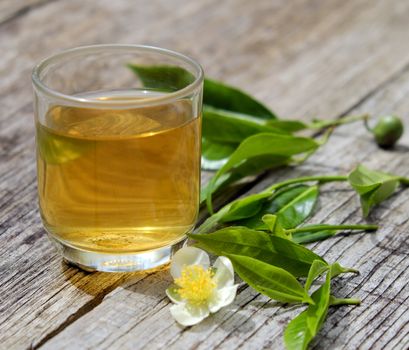 Green tea cup on wooden background with leaf and flower, green tea is good drink, healthy beverage can antioxidant, rich vitamin