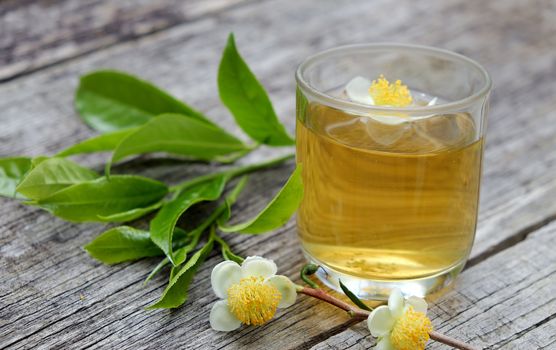 Green tea cup on wooden background with leaf and flower, green tea is good drink, healthy beverage can antioxidant, rich vitamin