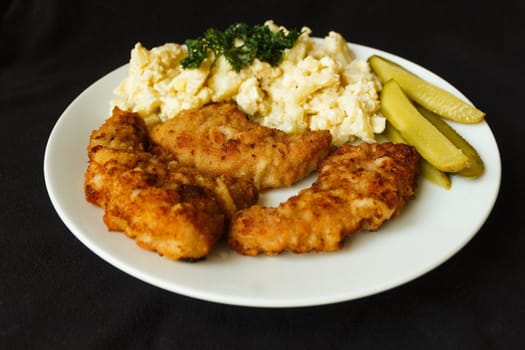 picture taken on Dec. 26, 2015 in Jablonec nad Nisou, Czech Republic schnitzel  and egg salad cucumber parsley white plate on a dark background