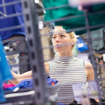 Beautiful caucasian woman shopping sportswear in sports store.