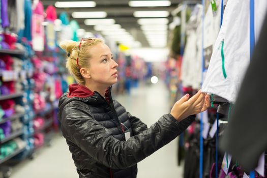 Beautiful caucasian woman shopping sportswear in sports store.
